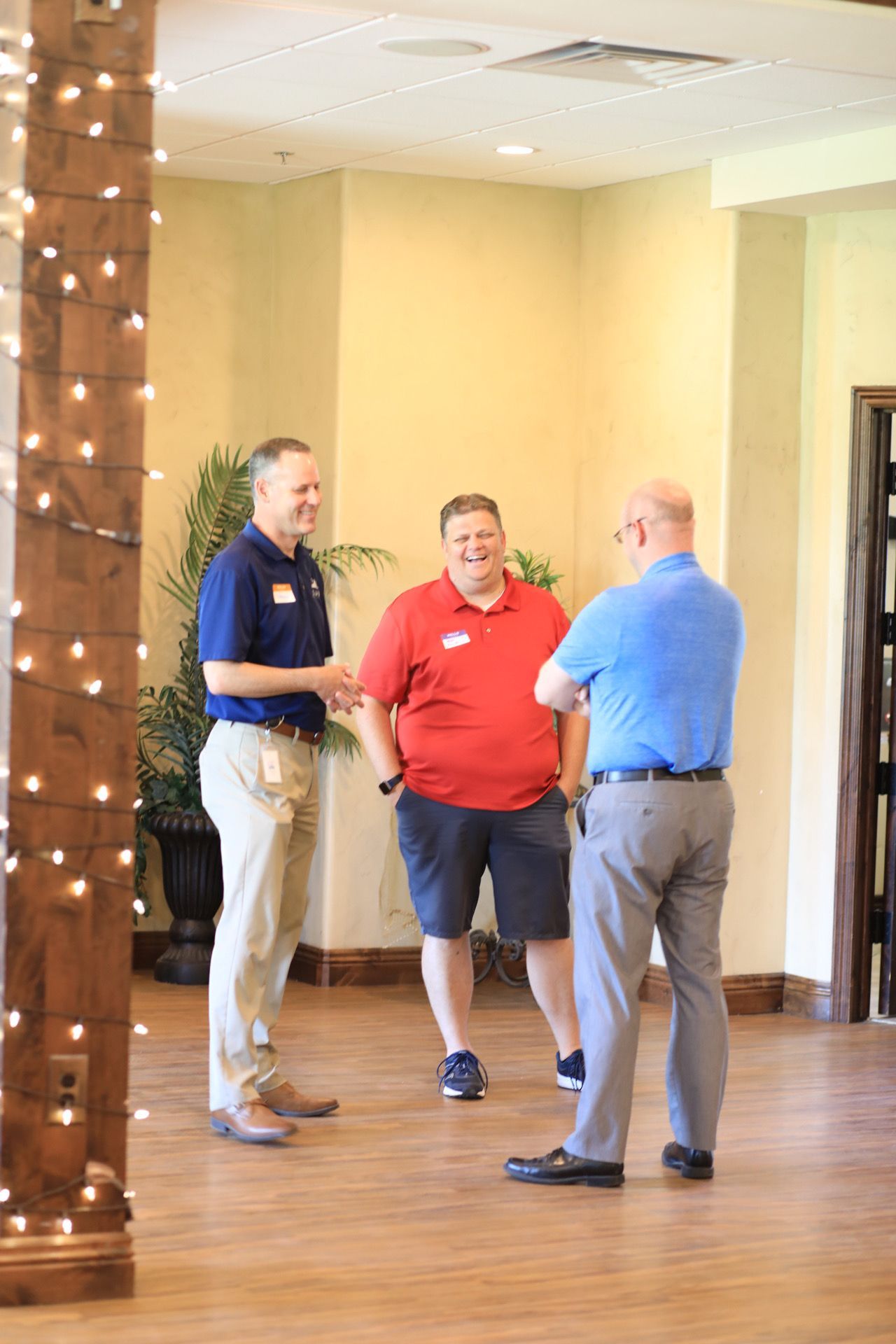 Three men are standing in a room talking to each other.