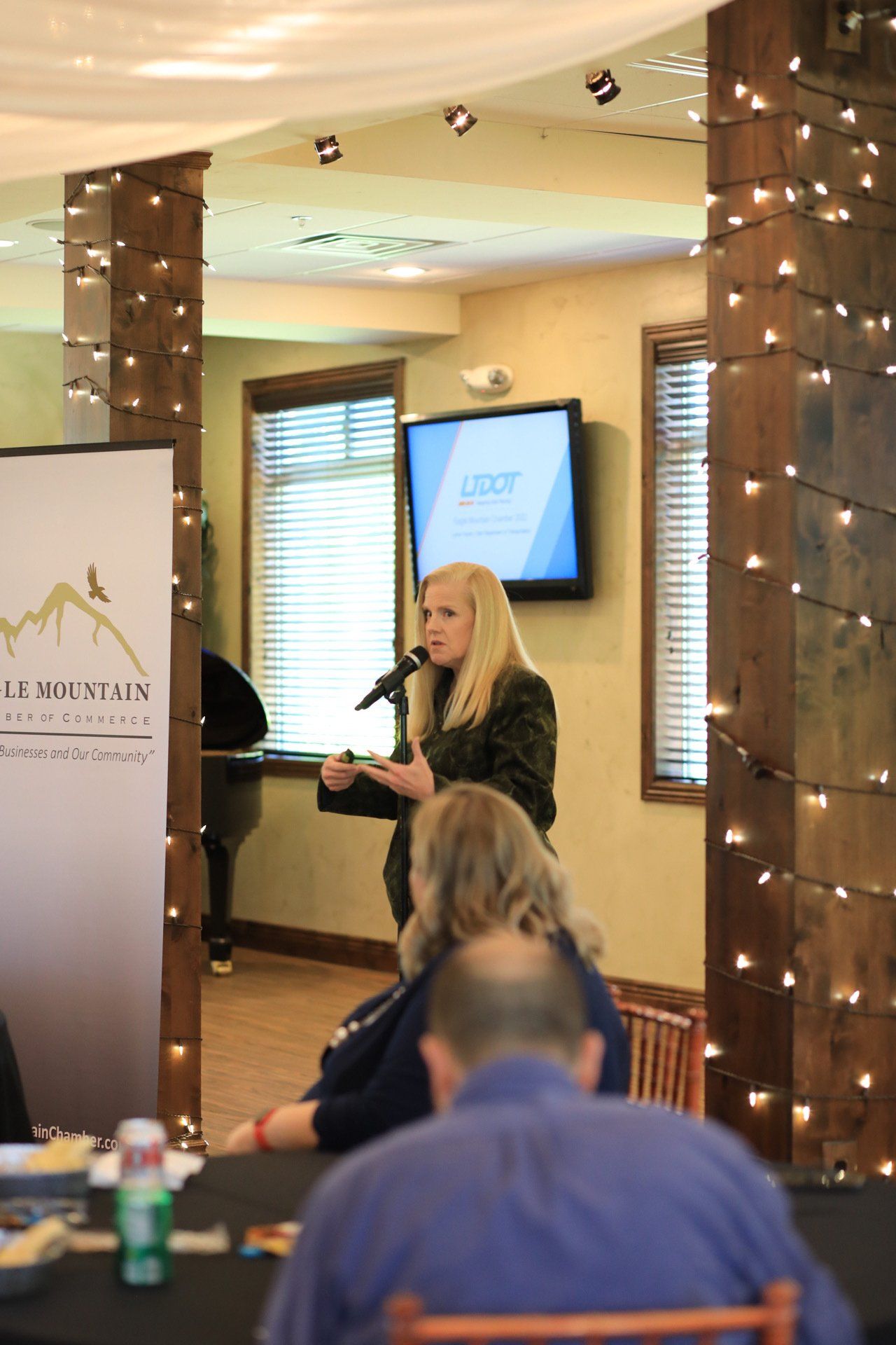 A woman is speaking into a microphone in front of a sign that says ascent