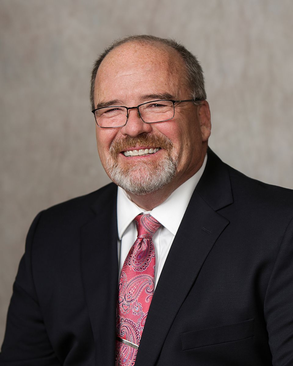A man in a suit and tie is smiling for the camera.