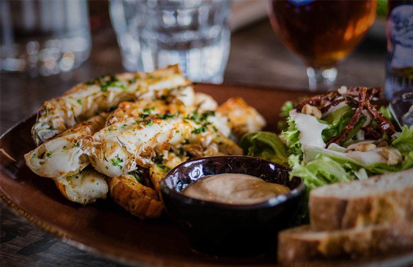 A plate of food with bread and a glass of beer on a table.