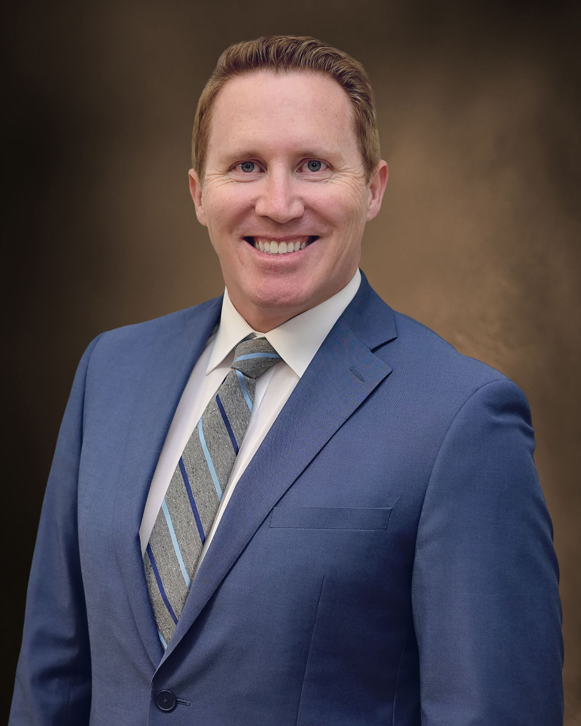 A man in a suit and tie is smiling for the camera.