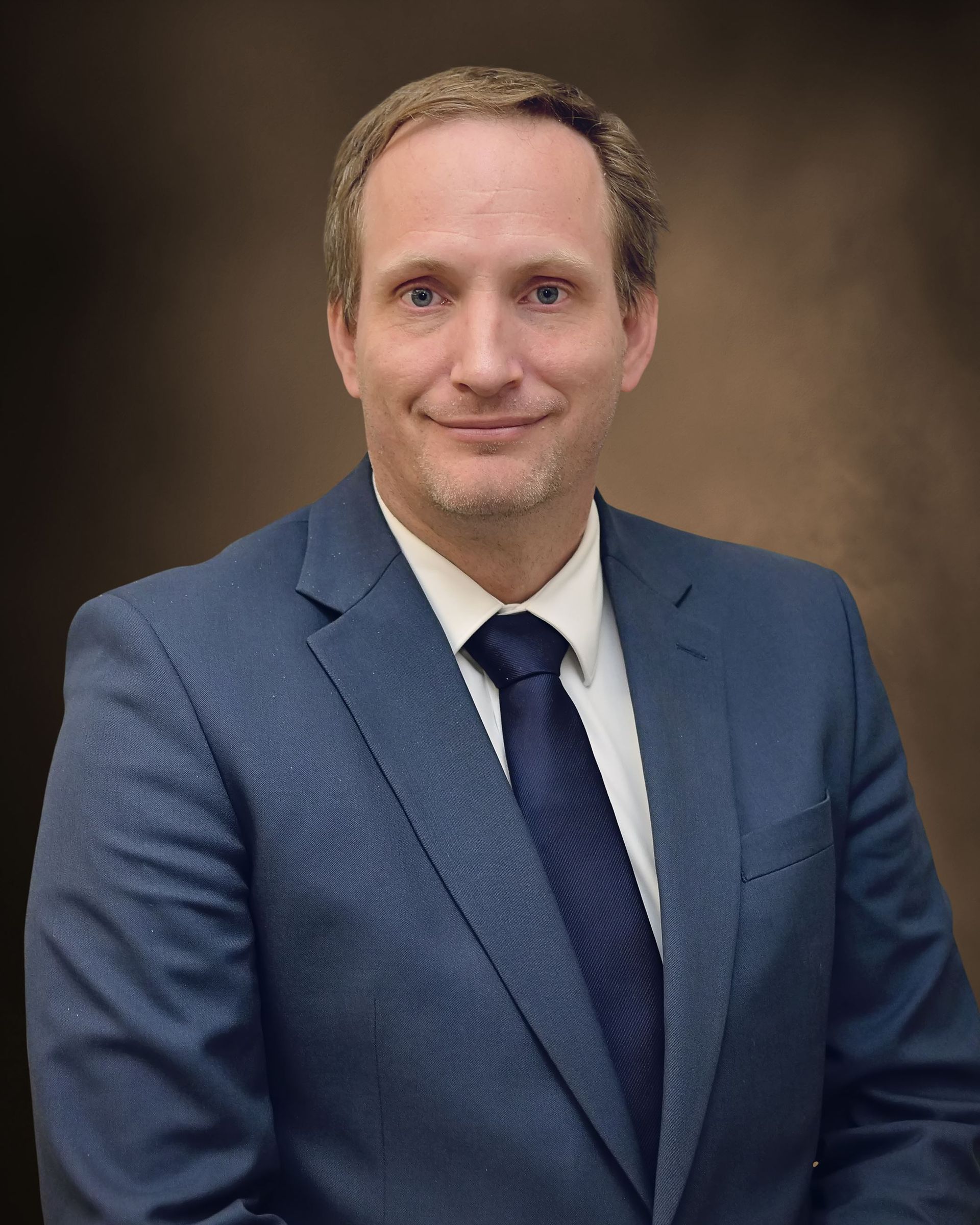 A man in a suit and tie is smiling for the camera.