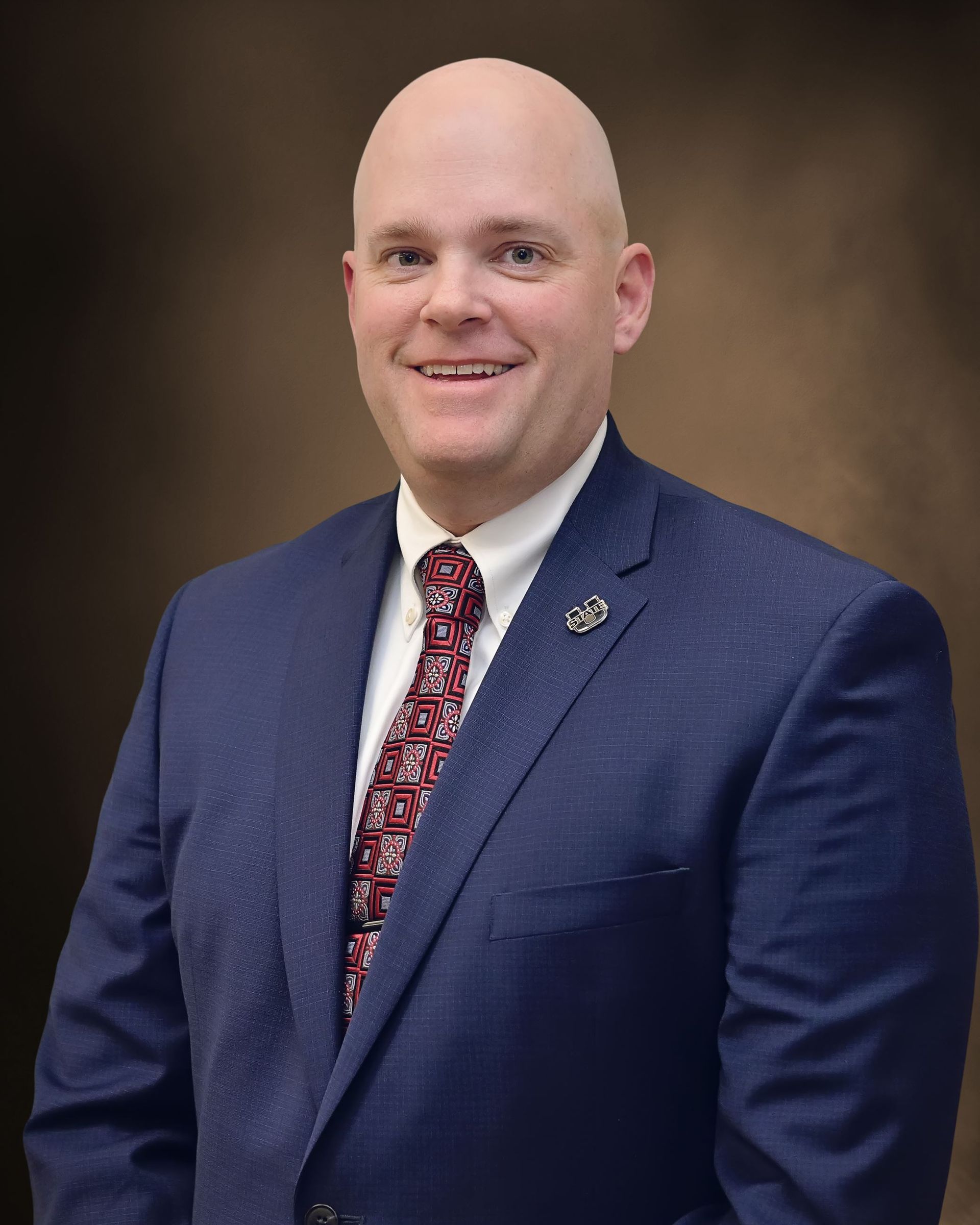 A man in a suit and tie is smiling for the camera.