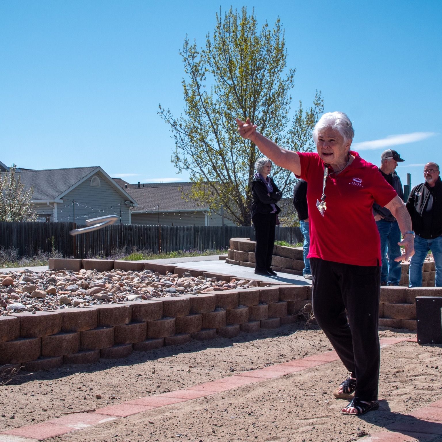 A woman in a red shirt is throwing a frisbee