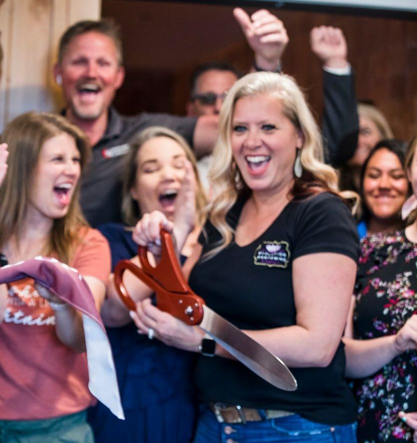 A woman in a black shirt is holding a pair of scissors