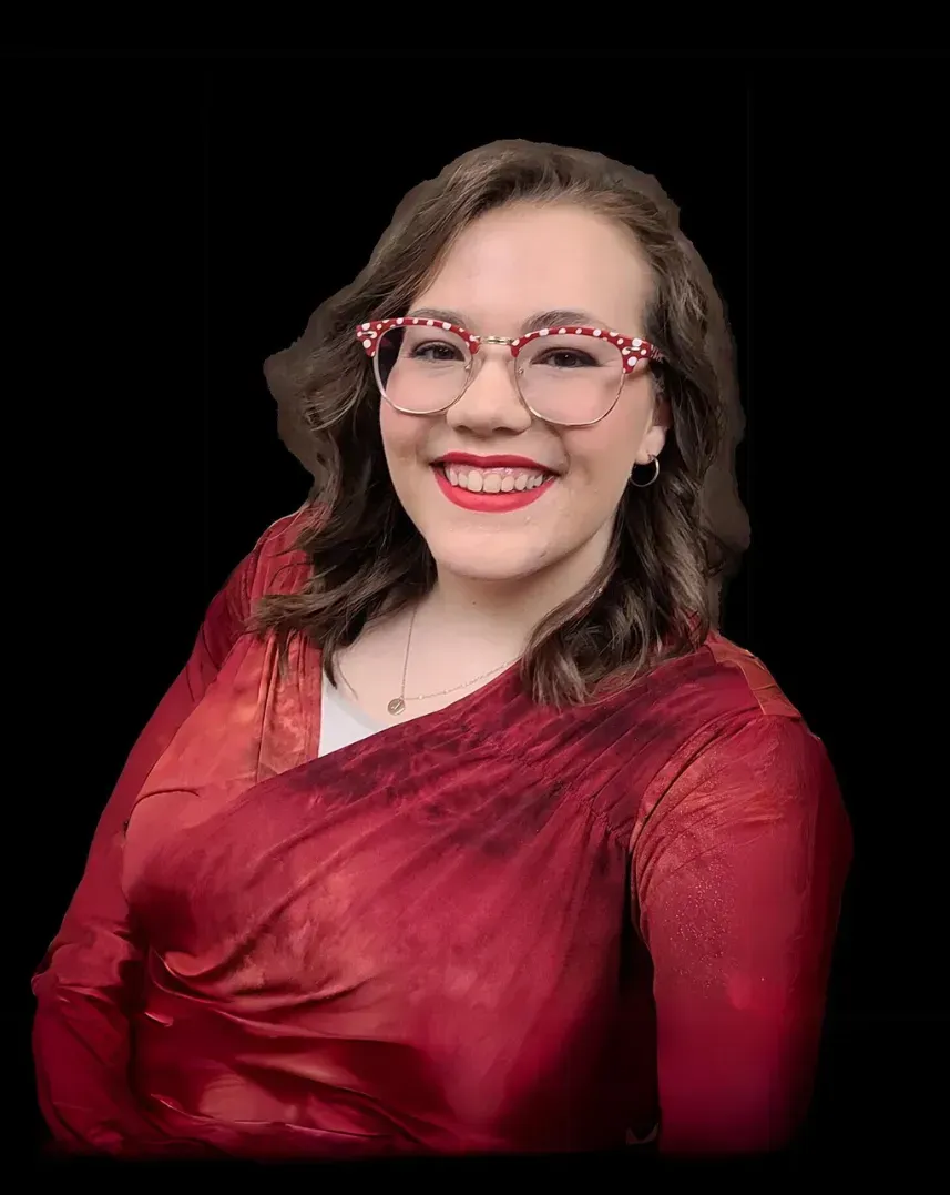 A woman with a big afro is smiling and holding her hair.