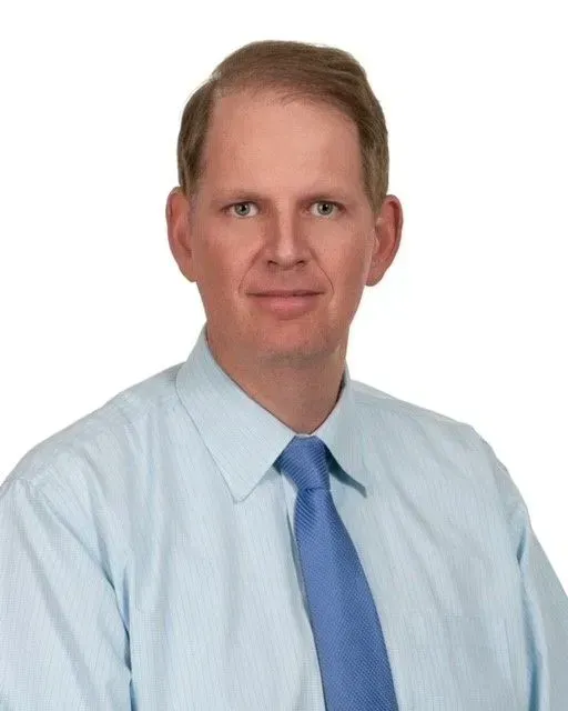 A young man with curly hair is holding a yellow television.