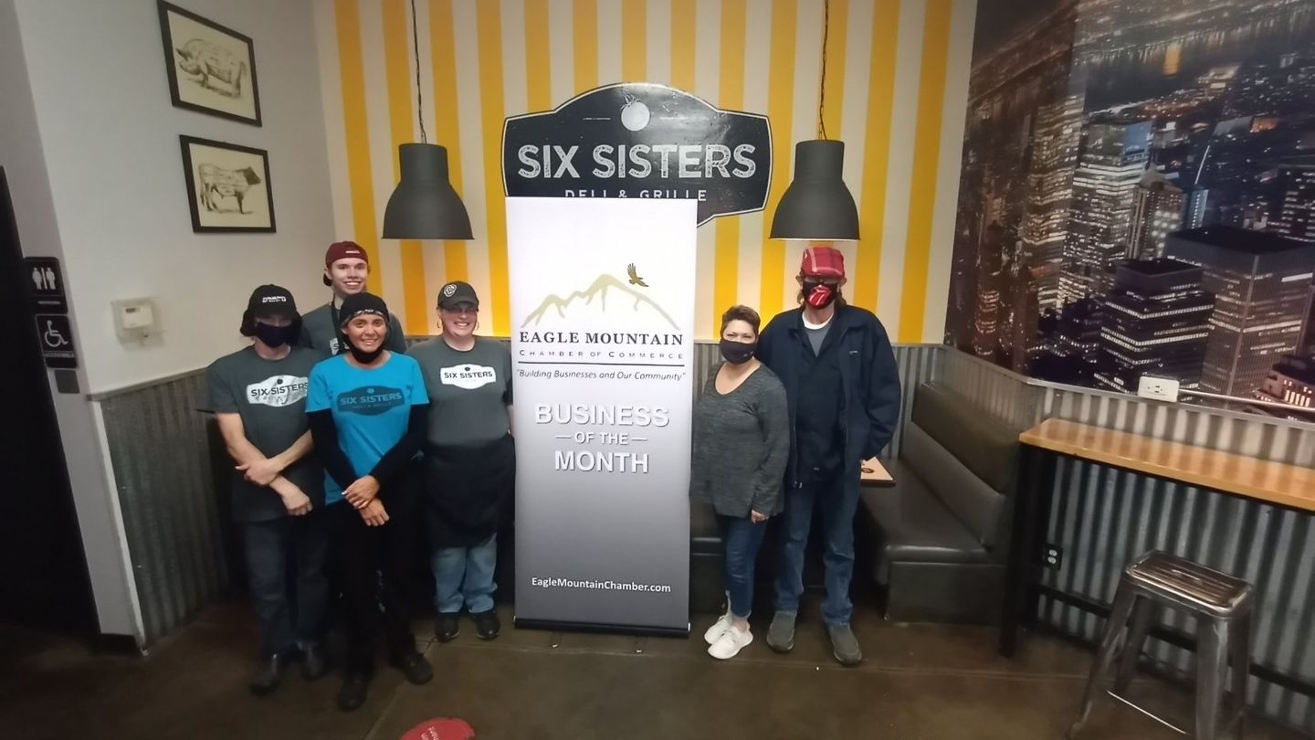 A group of people standing in front of a sign that says six sisters.