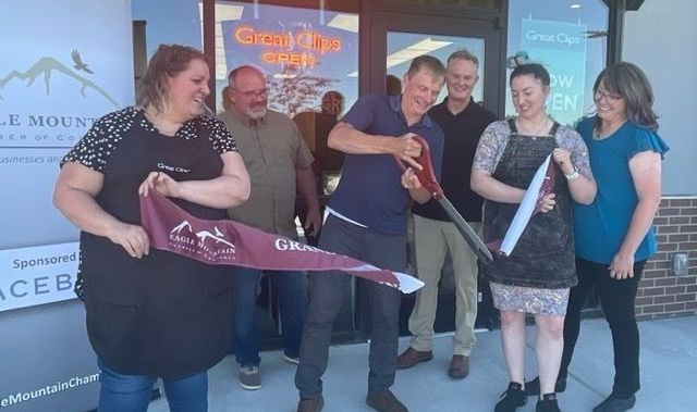 A group of people are standing in front of a store cutting a ribbon.