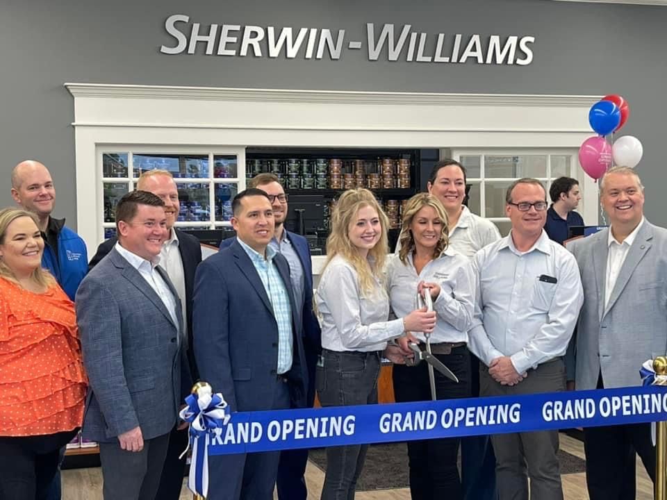 A group of people are standing in front of a blue ribbon.