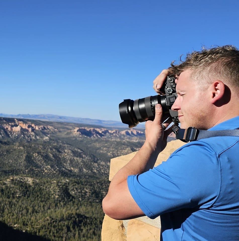 A man in a blue shirt is taking a picture with a camera