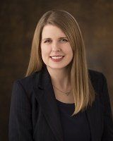 A woman in a suit is smiling for the camera.