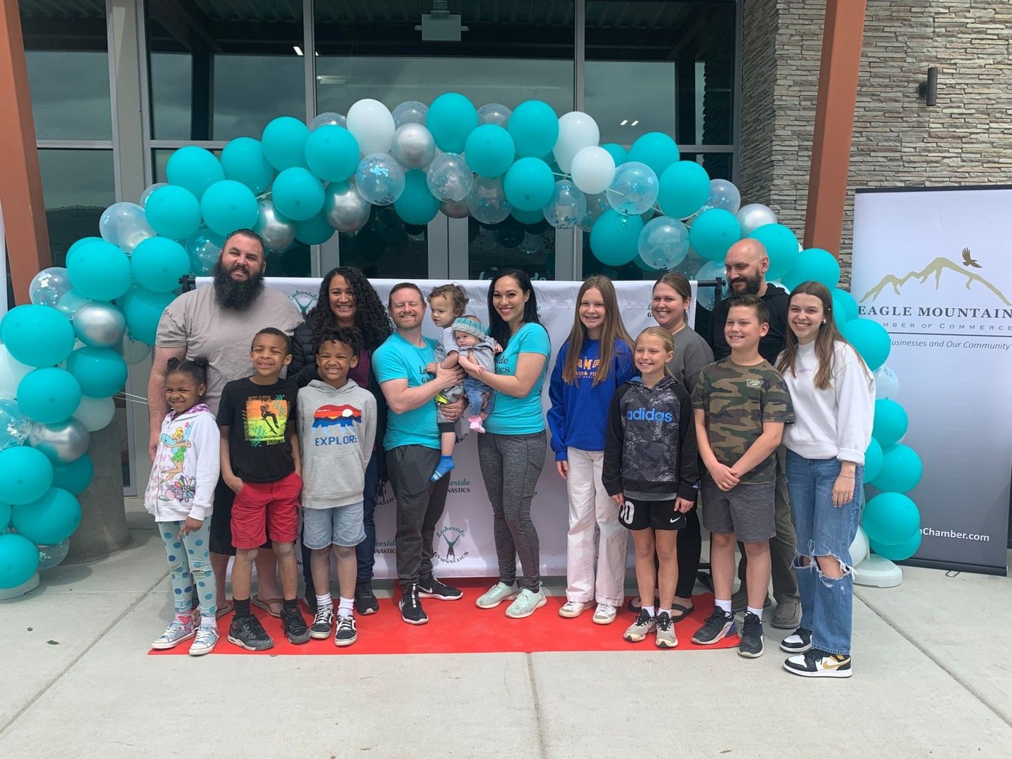 A large group of people are posing for a picture in front of a building with balloons.