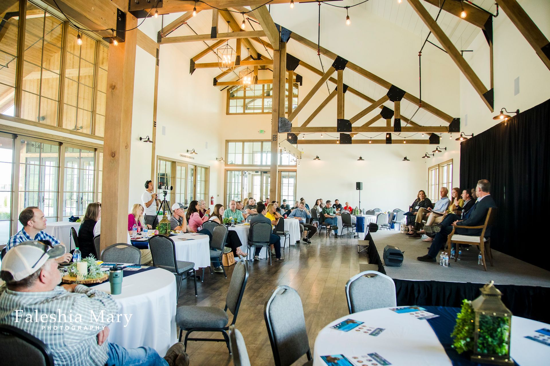A group of people are sitting at tables in a large room.