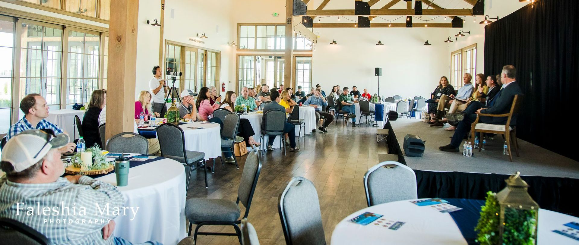 A group of people are sitting at tables in a large room.