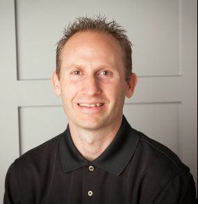 A man is holding a dog in his arms and the dog is wearing a sweater.