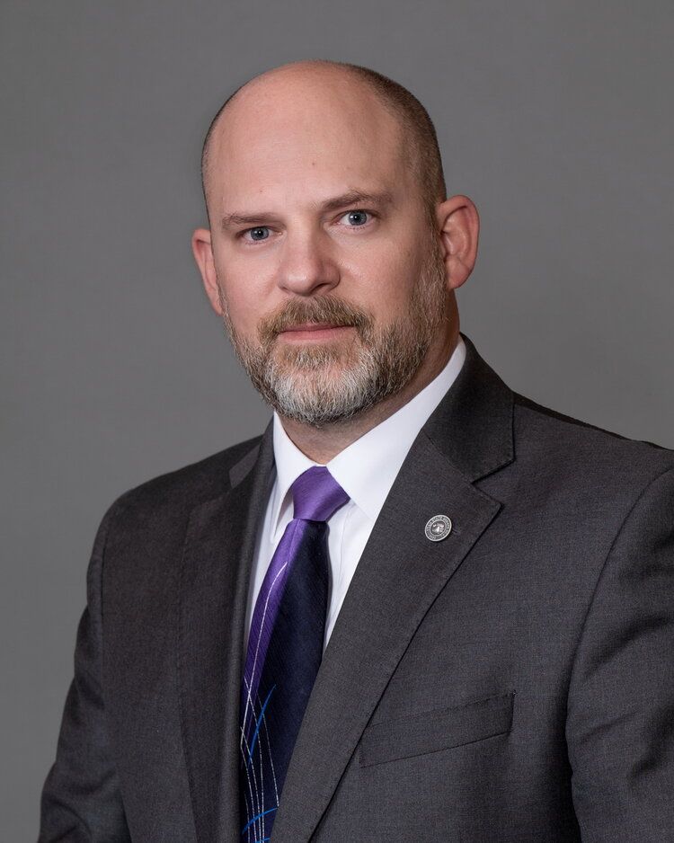 A bald man with a beard is wearing a suit and tie.
