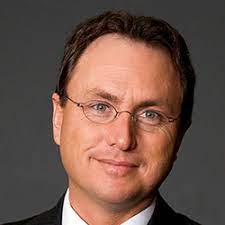 A man wearing glasses and a suit is smiling for the camera.