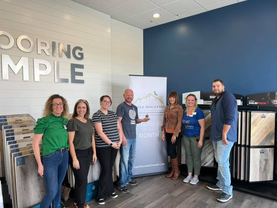 A group of people are standing in front of a sign that says doing simple.