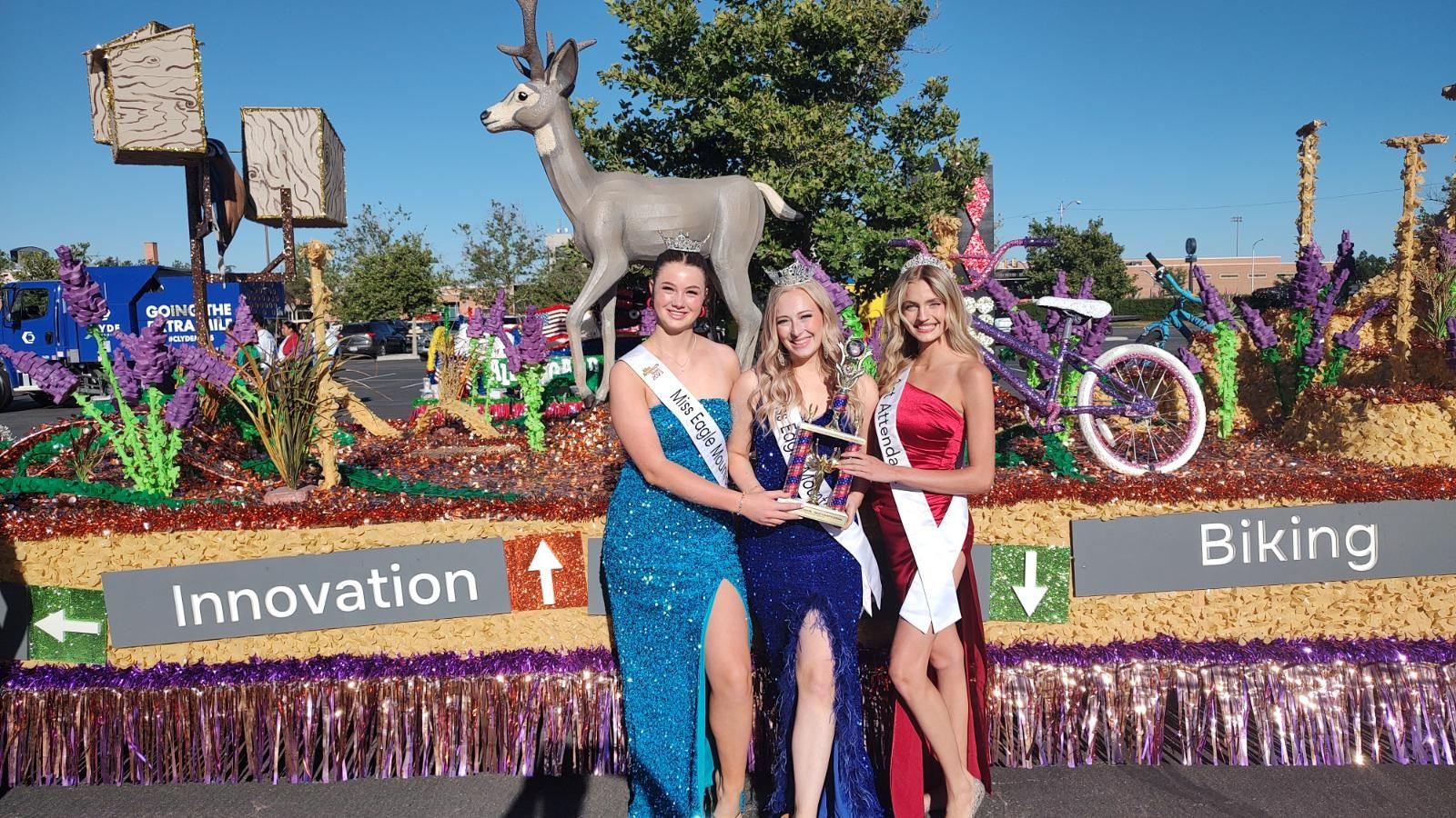 Three women are standing in front of a float that says innovation and biking