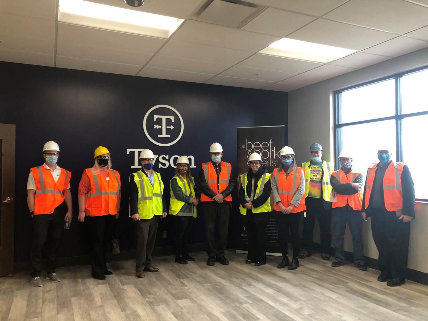 A group of construction workers wearing hard hats and safety vests are standing in a room.