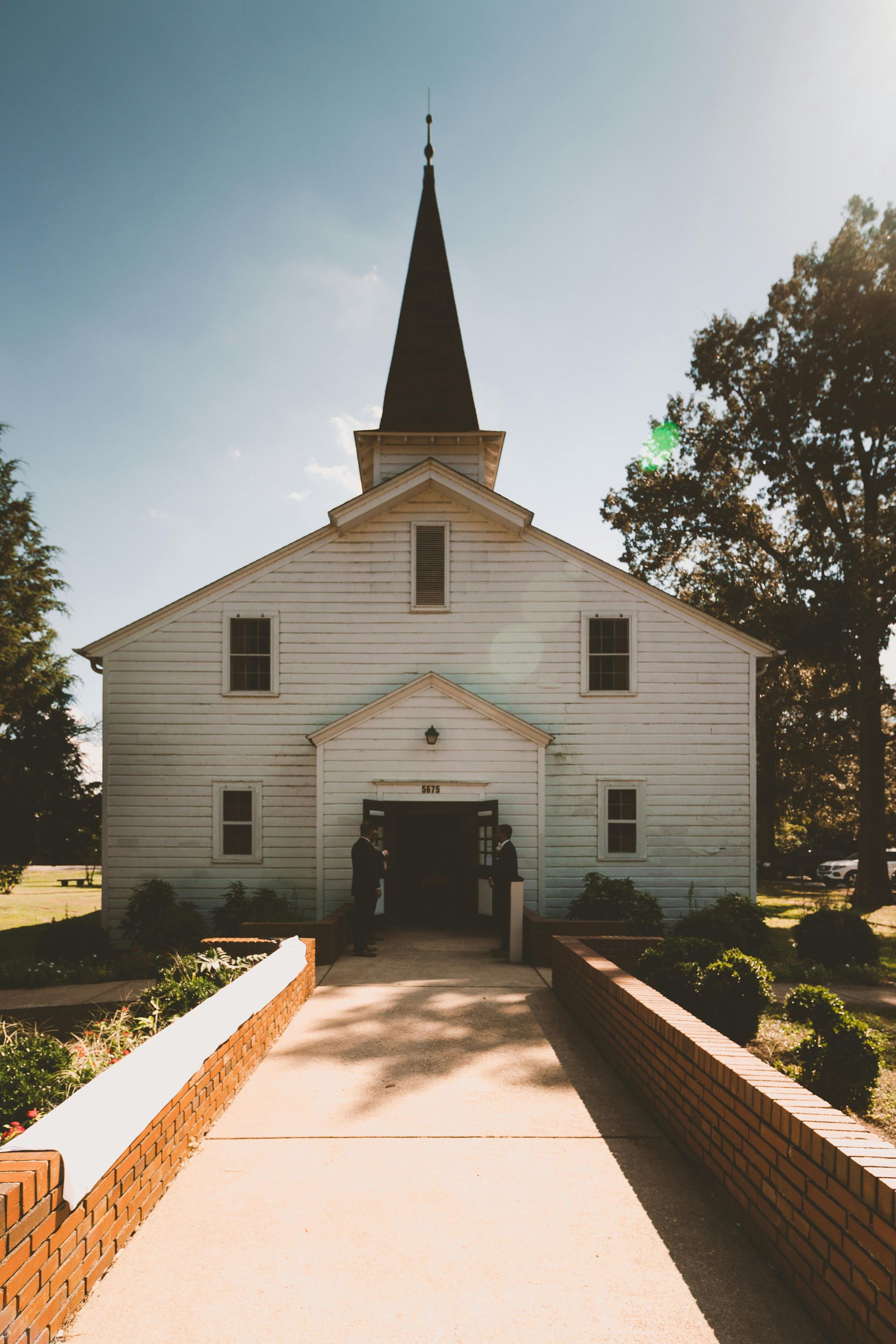 A white church with a steeple and a walkway leading to it