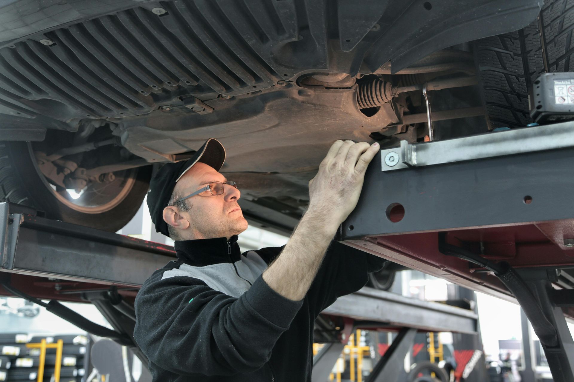A man is working under a car on a lift.