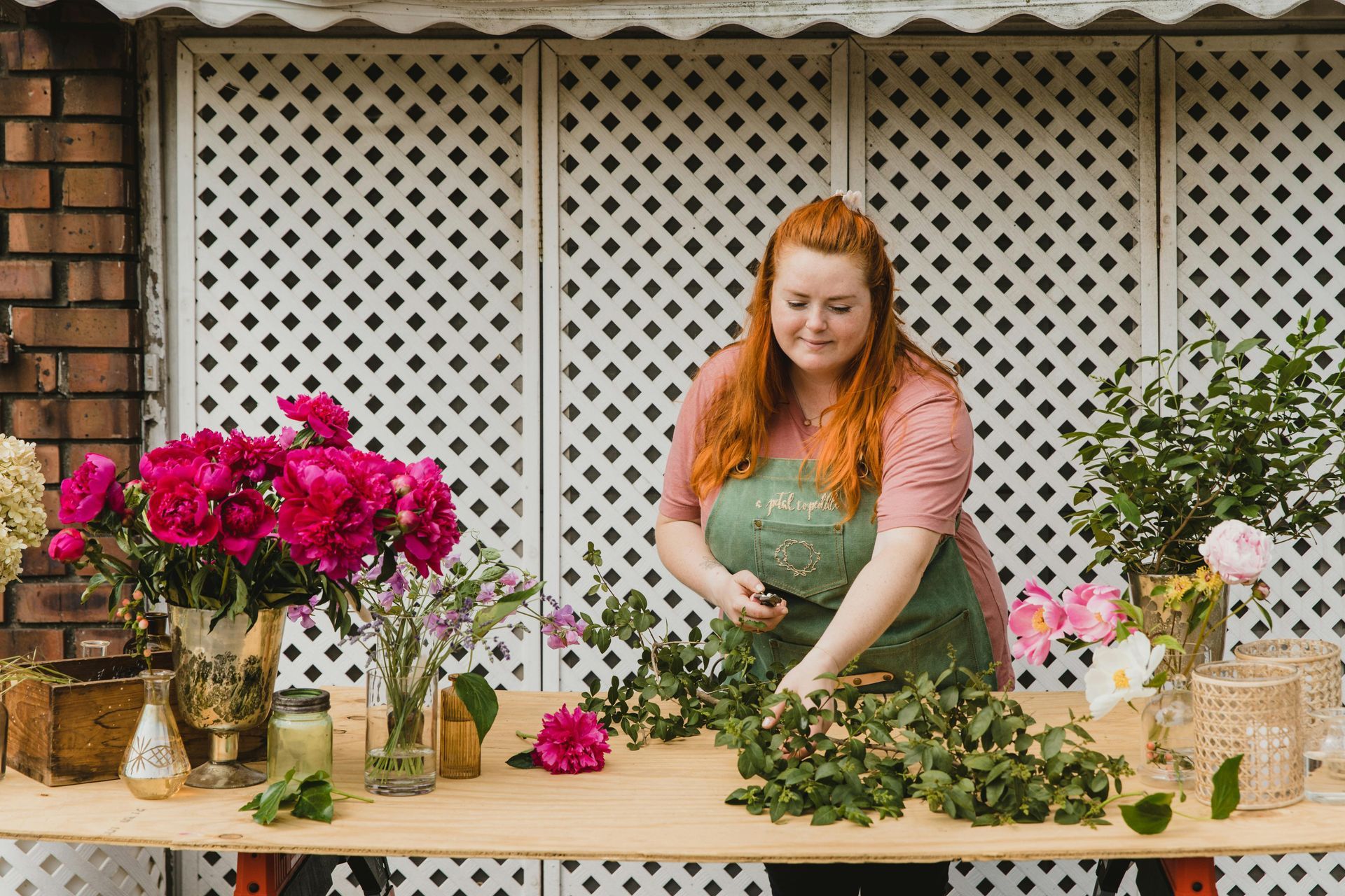 A woman is standing at a table with flowers in vases.