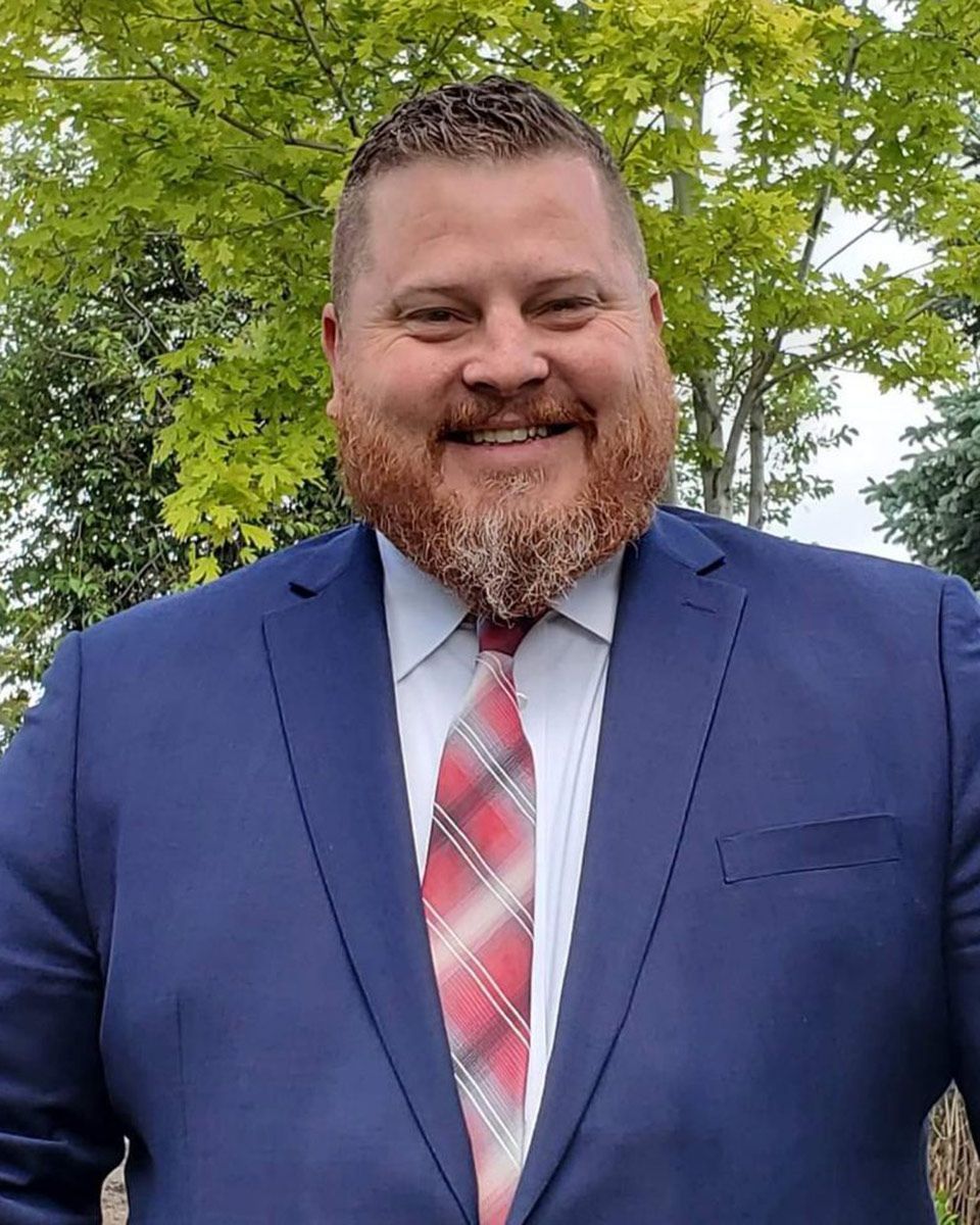 A man with a beard is wearing a suit and tie and smiling.