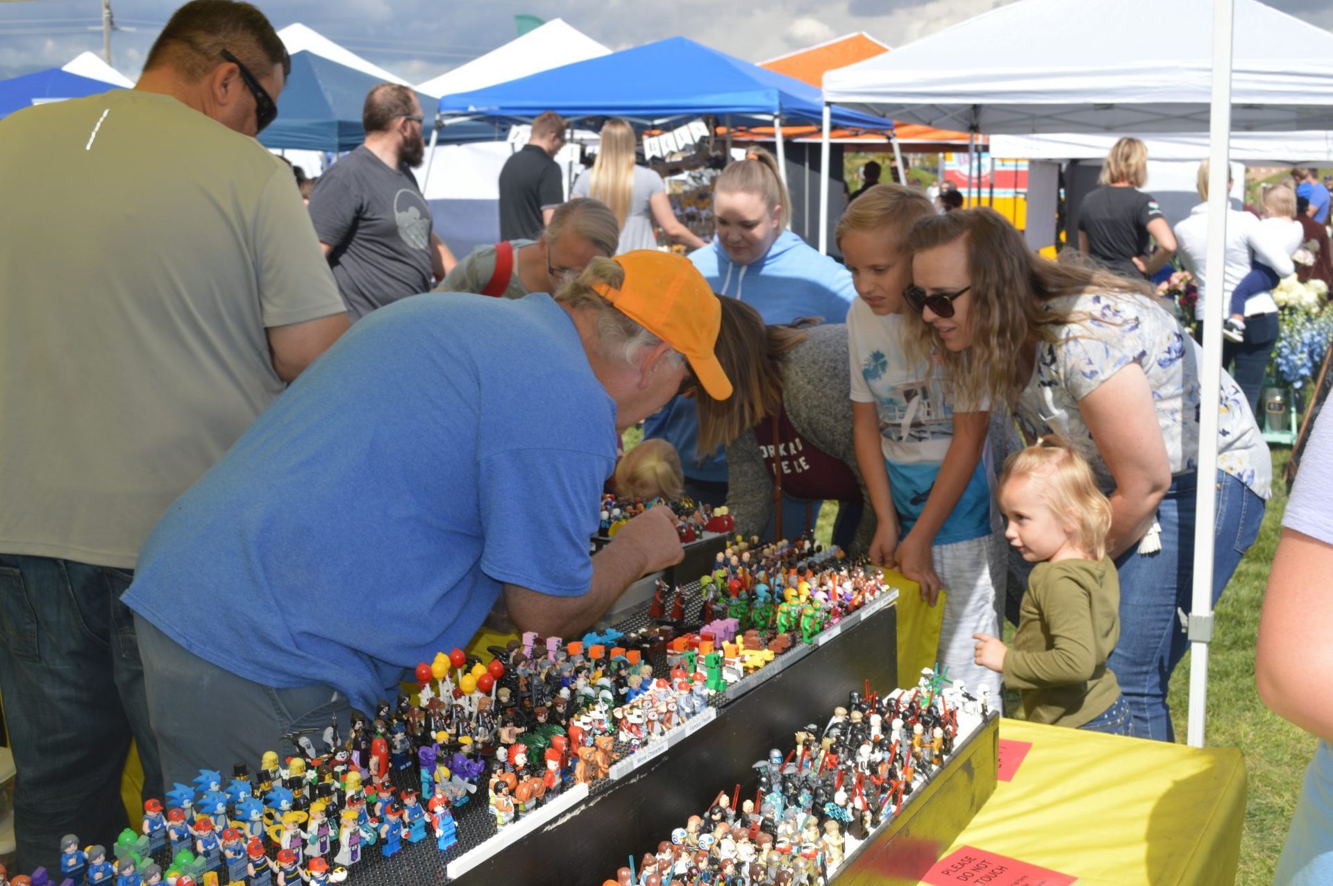 A group of people are looking at a table full of toy figures.