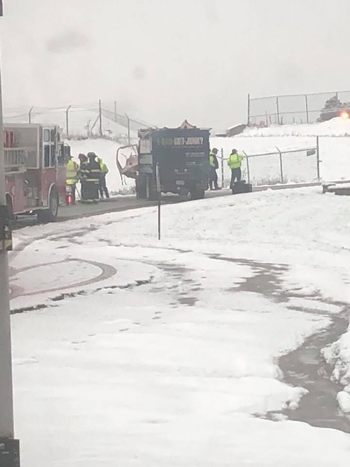 Firefighters and workers near a truck at a snowy site; a fire truck is present.