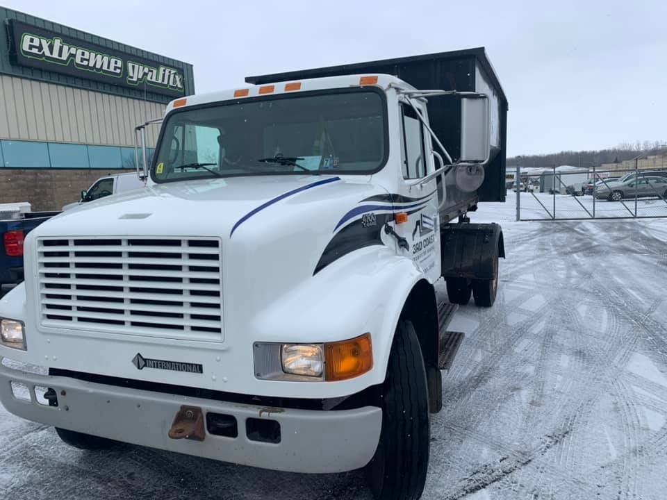 White dump truck parked on a snow-covered lot. 
