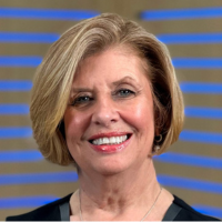 A woman with short blonde hair is smiling and wearing a black shirt.