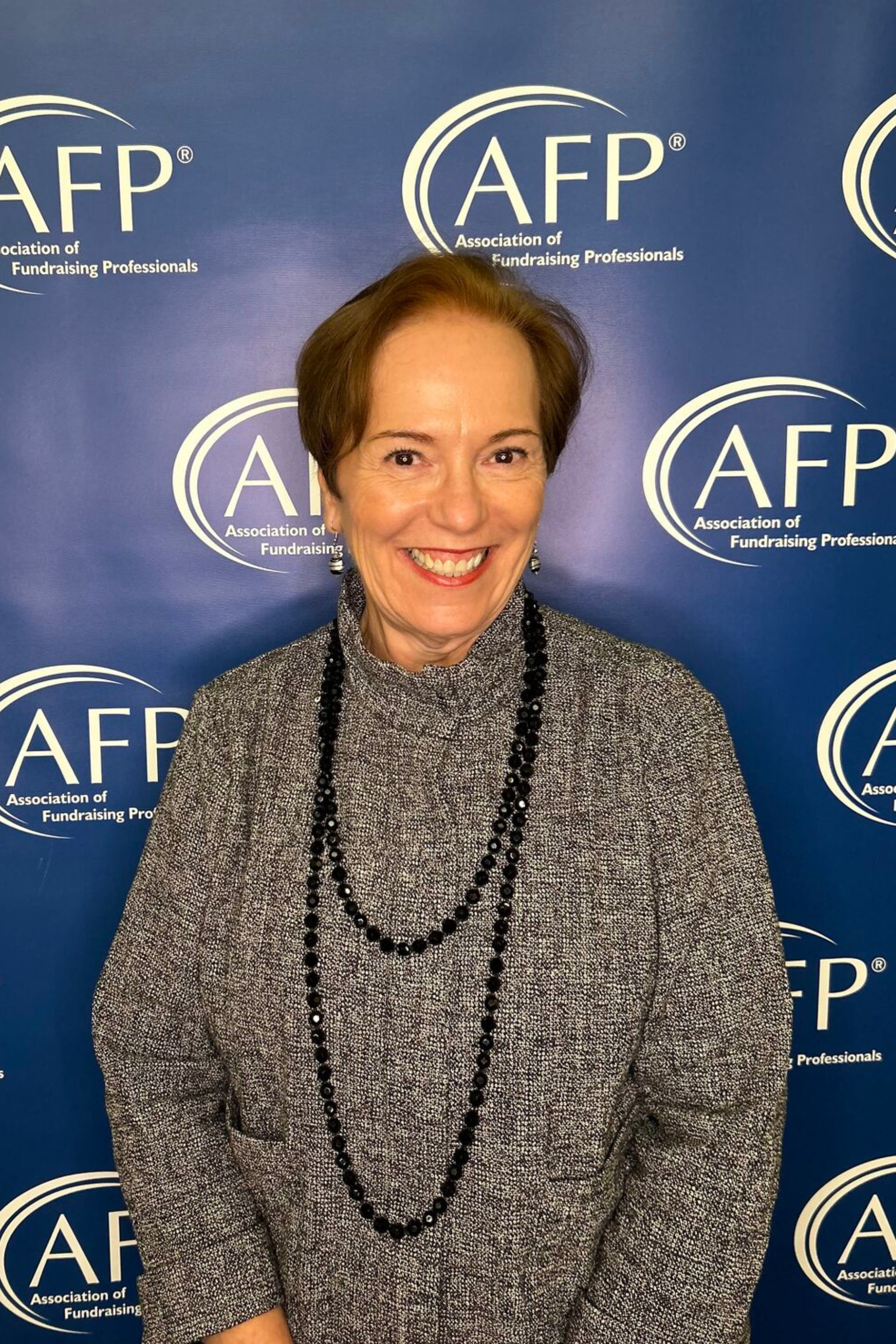A woman is smiling in front of a wall that says afp