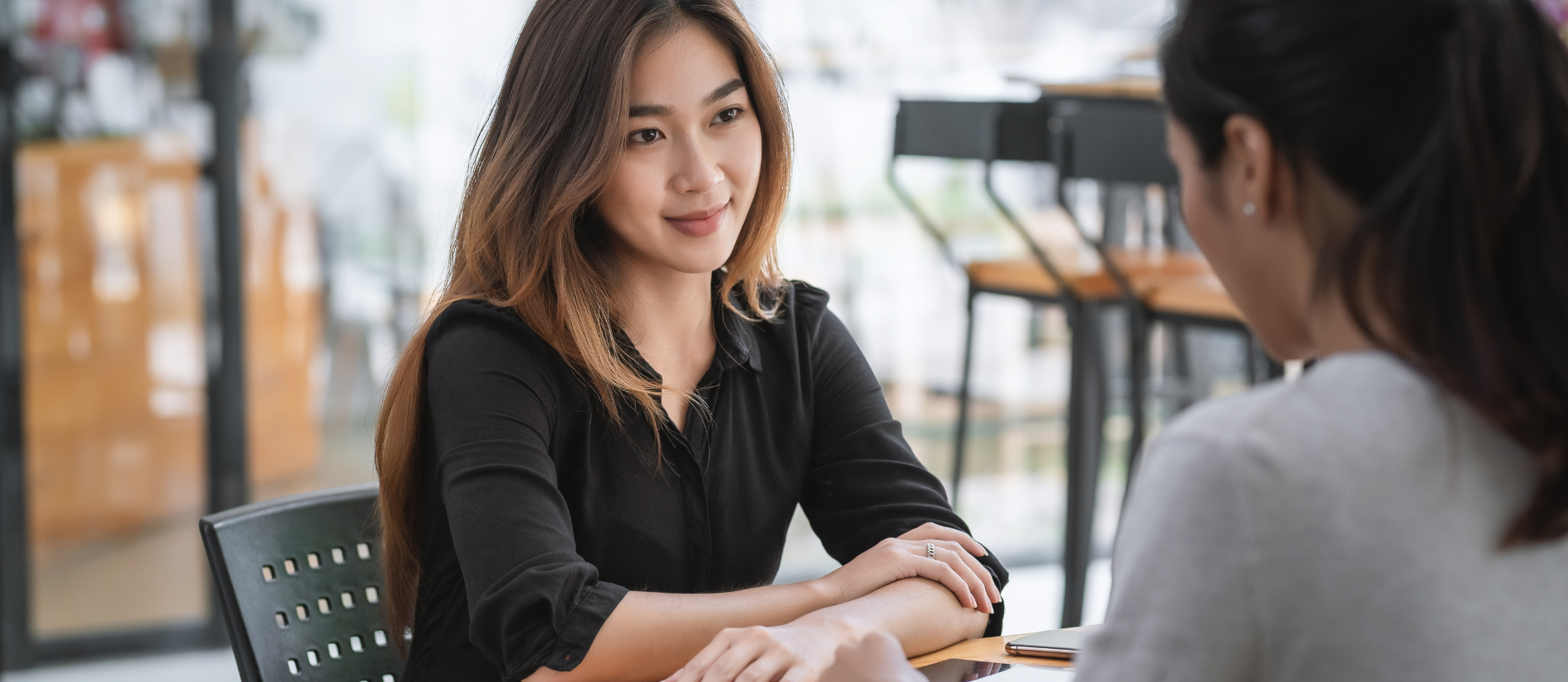 Two women are sitting at a table having a conversation.