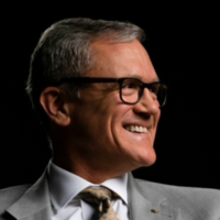 A man wearing glasses and a suit is smiling