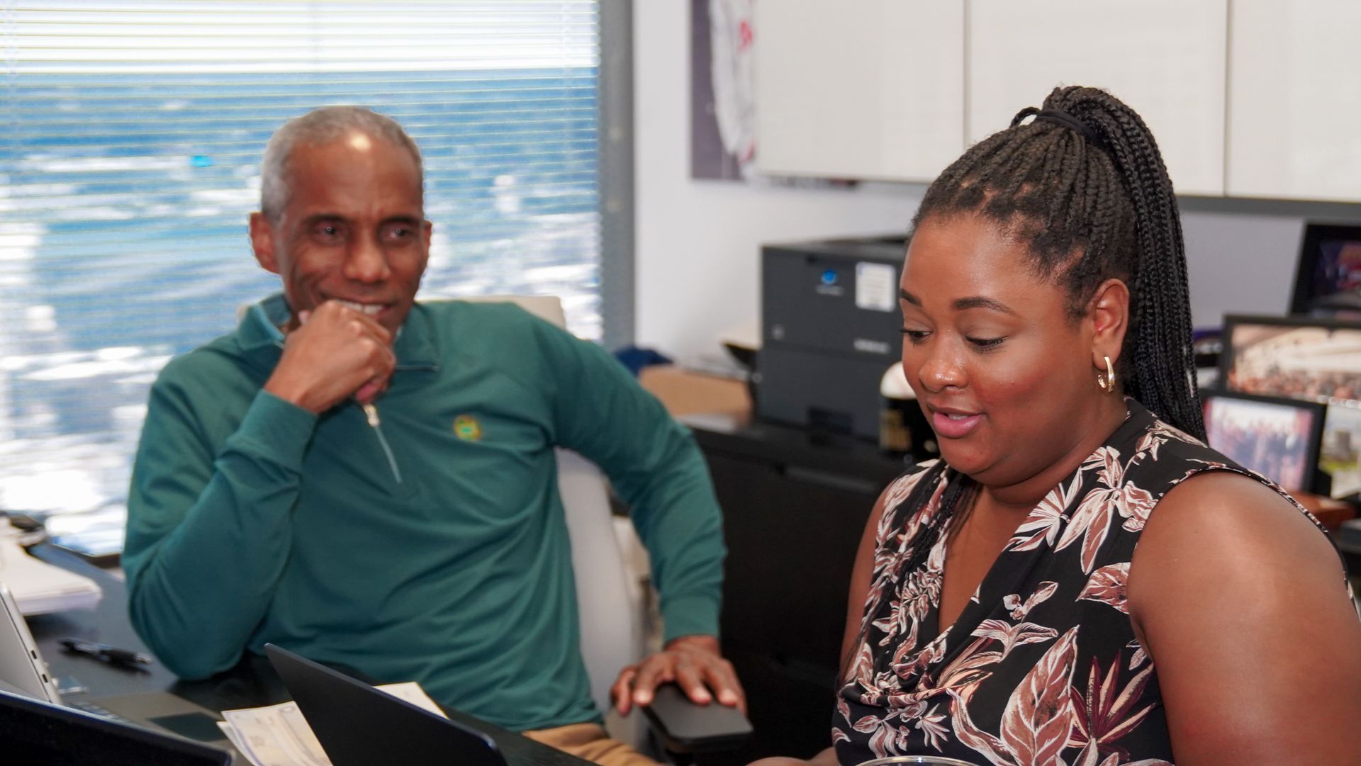 A man is leaning against a wall while looking at his cell phone.
