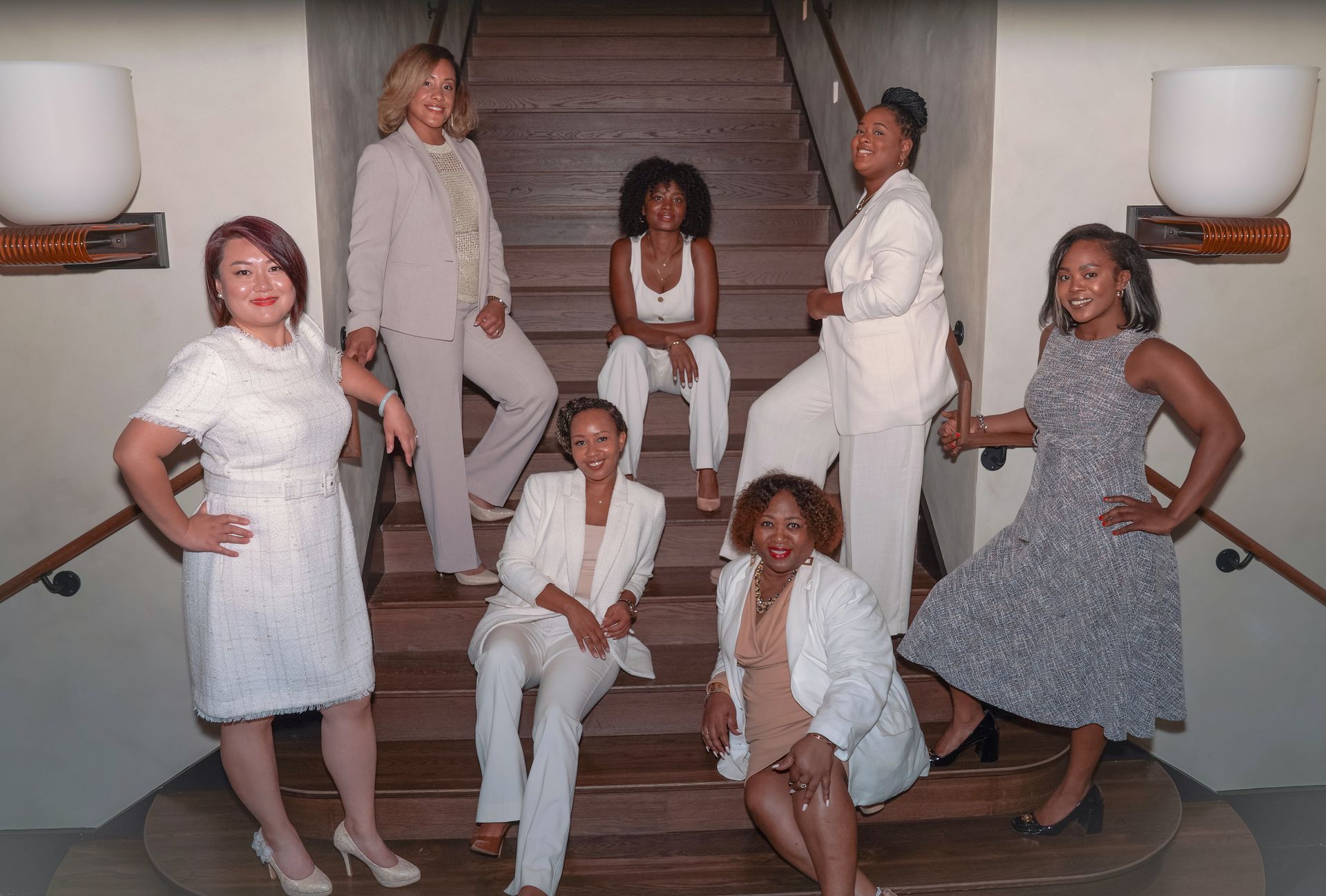 A diverse group of professional people in formal business attire pose together outdoors on a paved terrace.