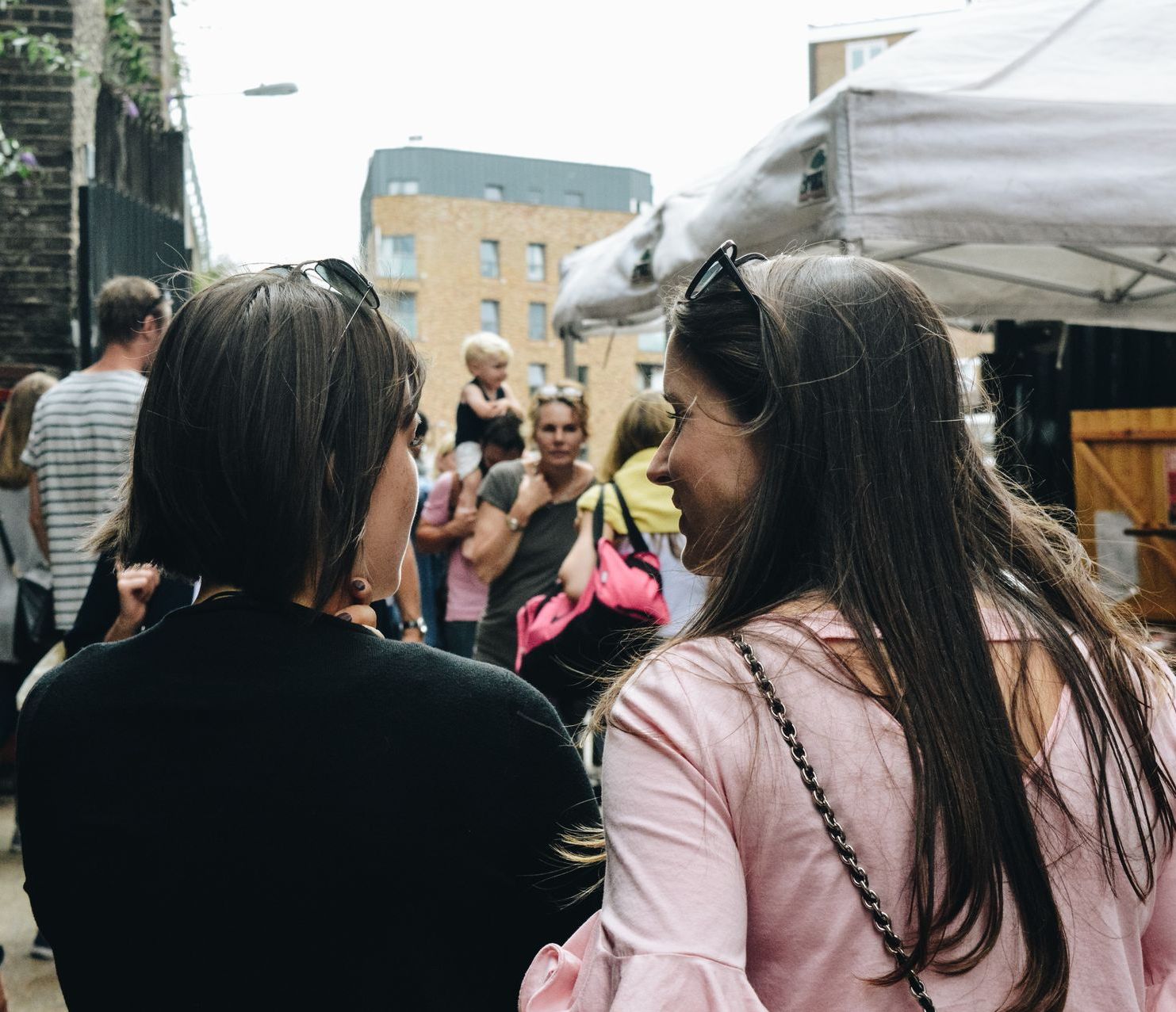 Two women are standing next to each other in front of a crowd of people.