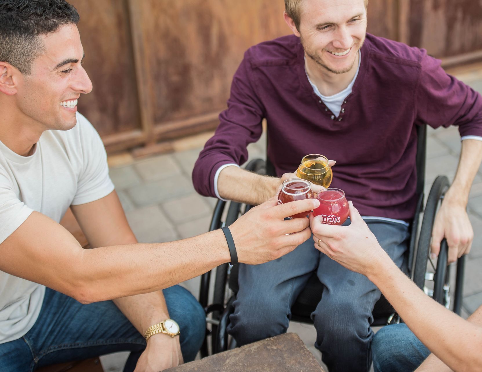 A man in a wheelchair is toasting with his friends