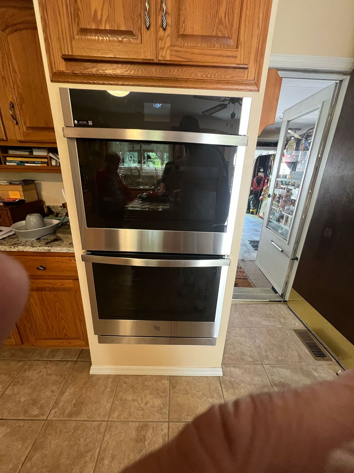 Three stainless steel ovens and a microwave are stacked on top of each other in a kitchen.