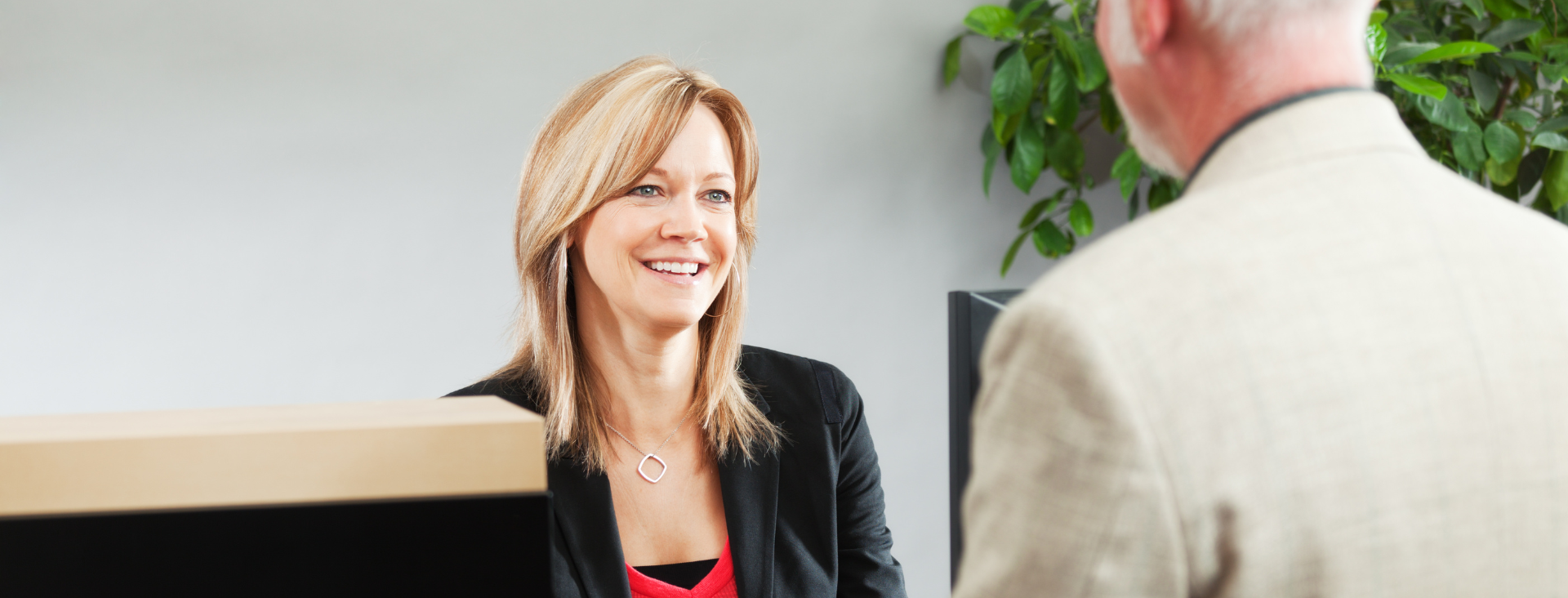 A woman is talking to a man at a counter in a bank