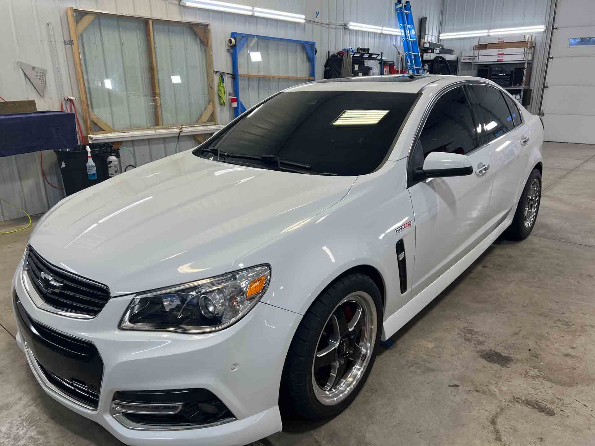 A white chevrolet caprice is parked in a garage.