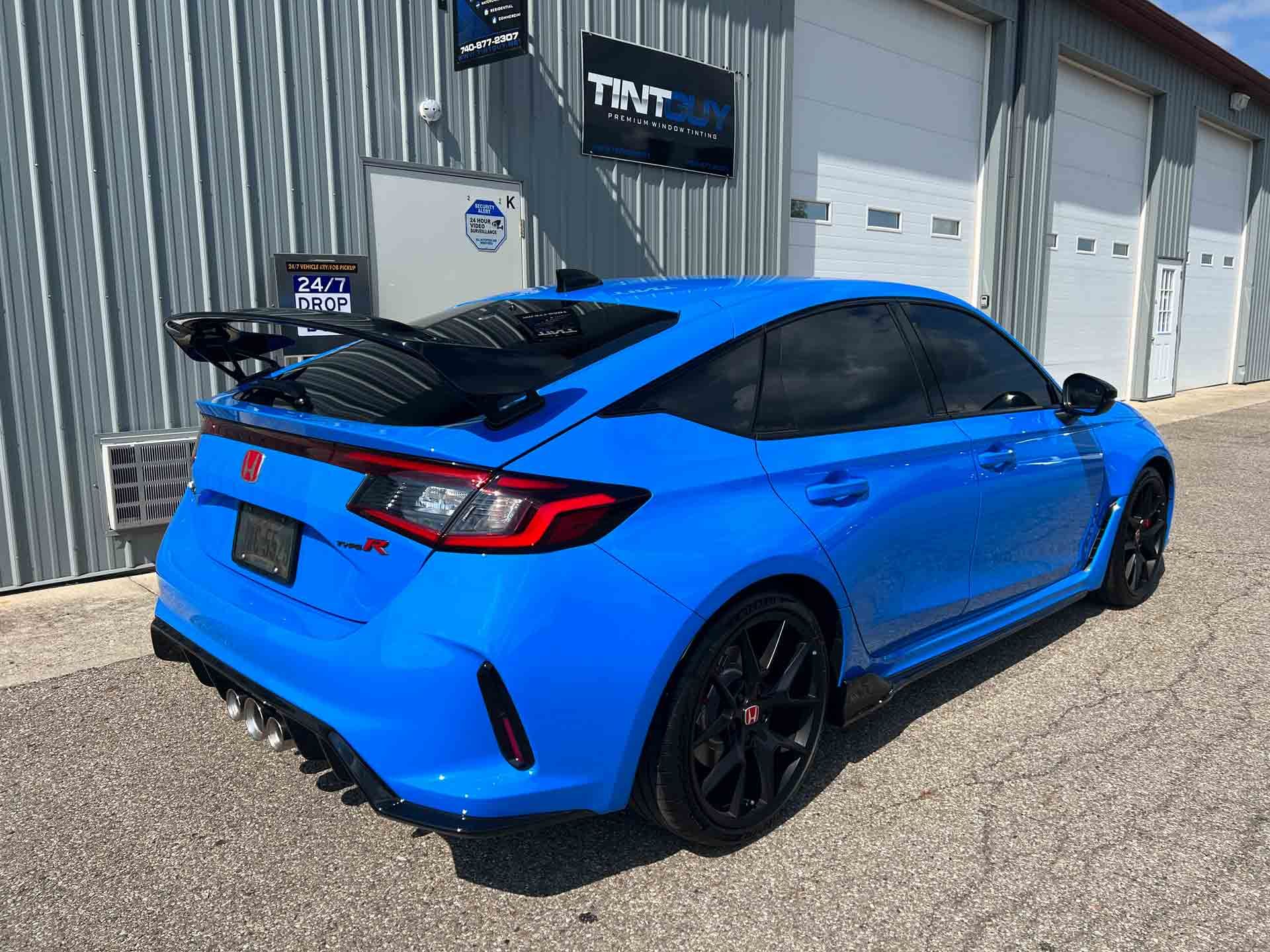 A blue car is parked in front of a garage.