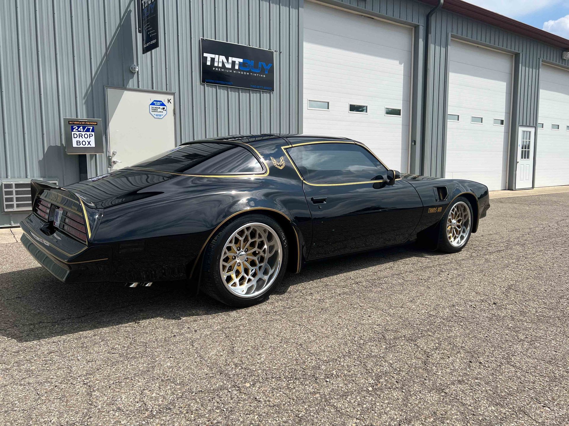 A black car is parked in front of a garage.