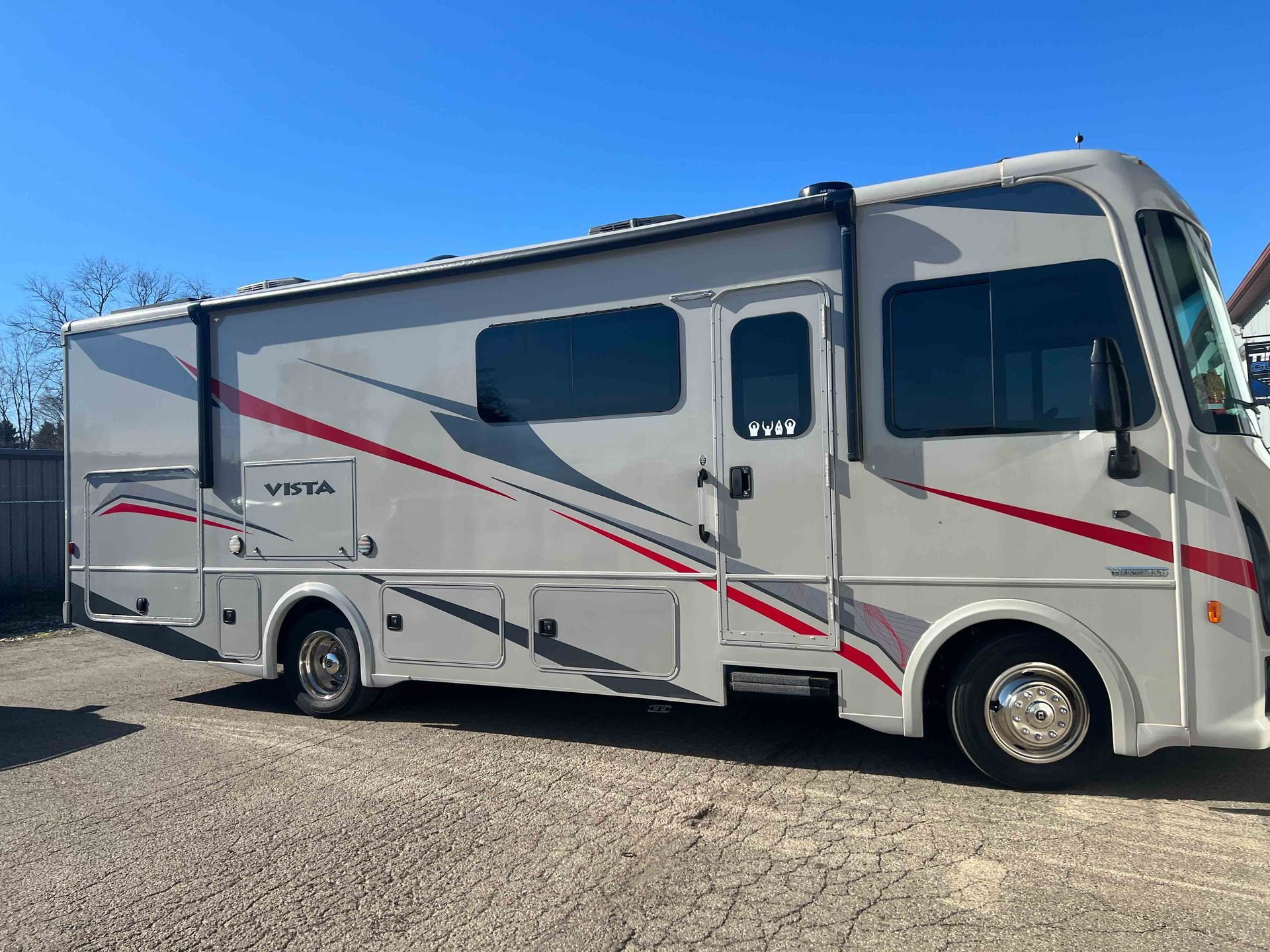 A white and red rv is parked in a gravel lot.