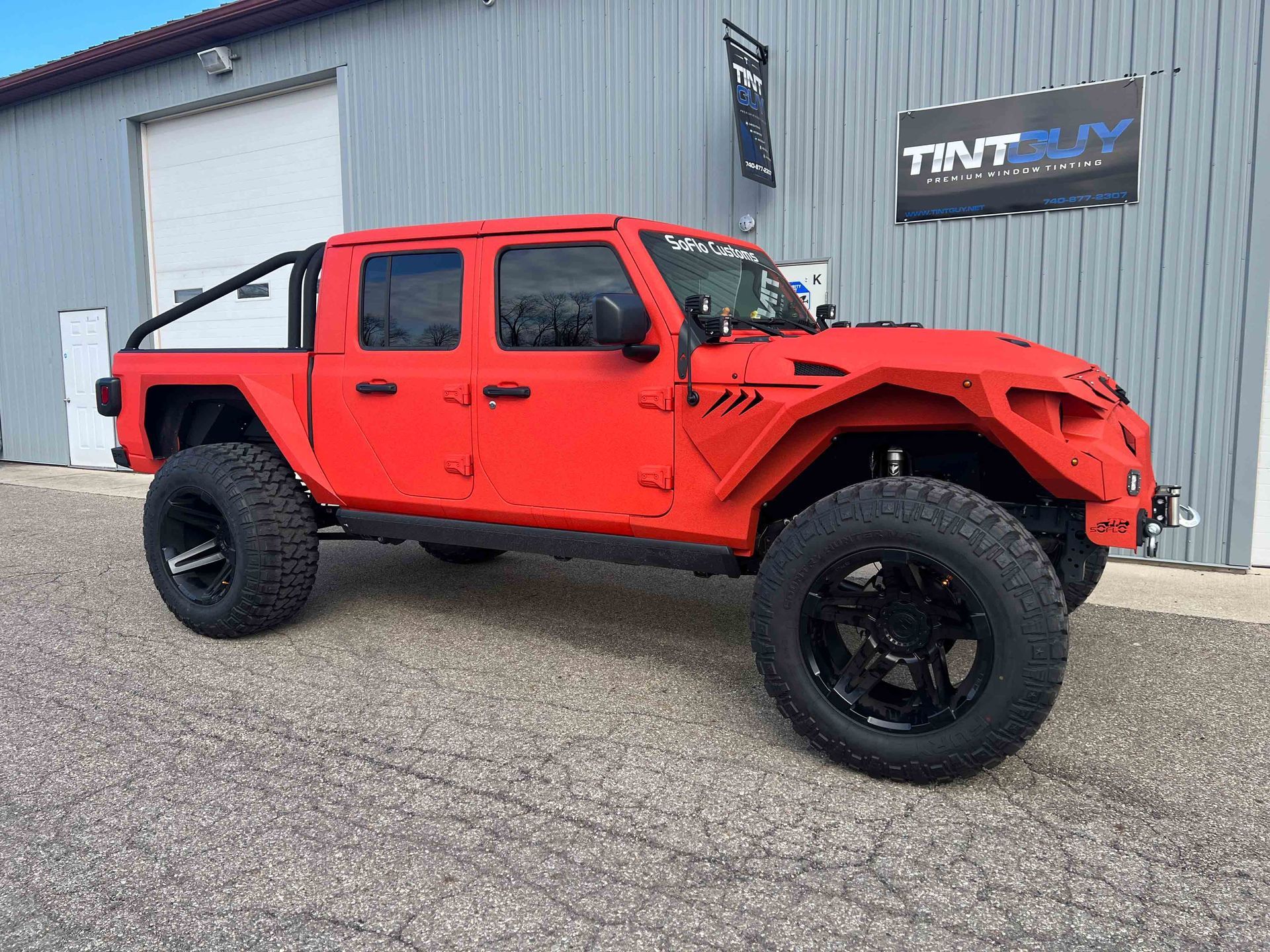 A red jeep is parked in front of a building.