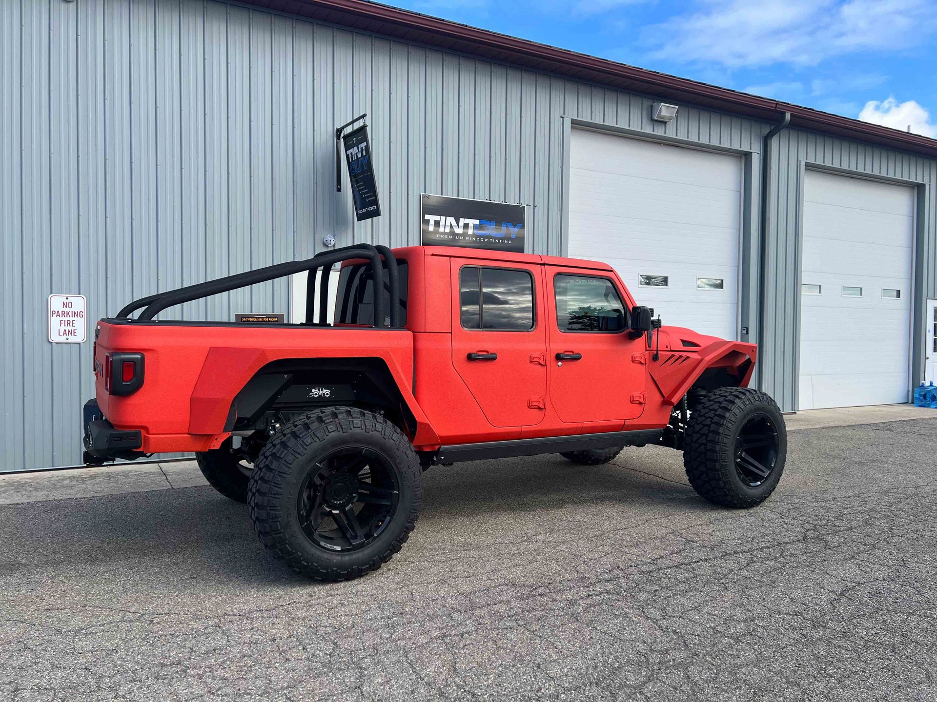 A red jeep is parked in front of a building.