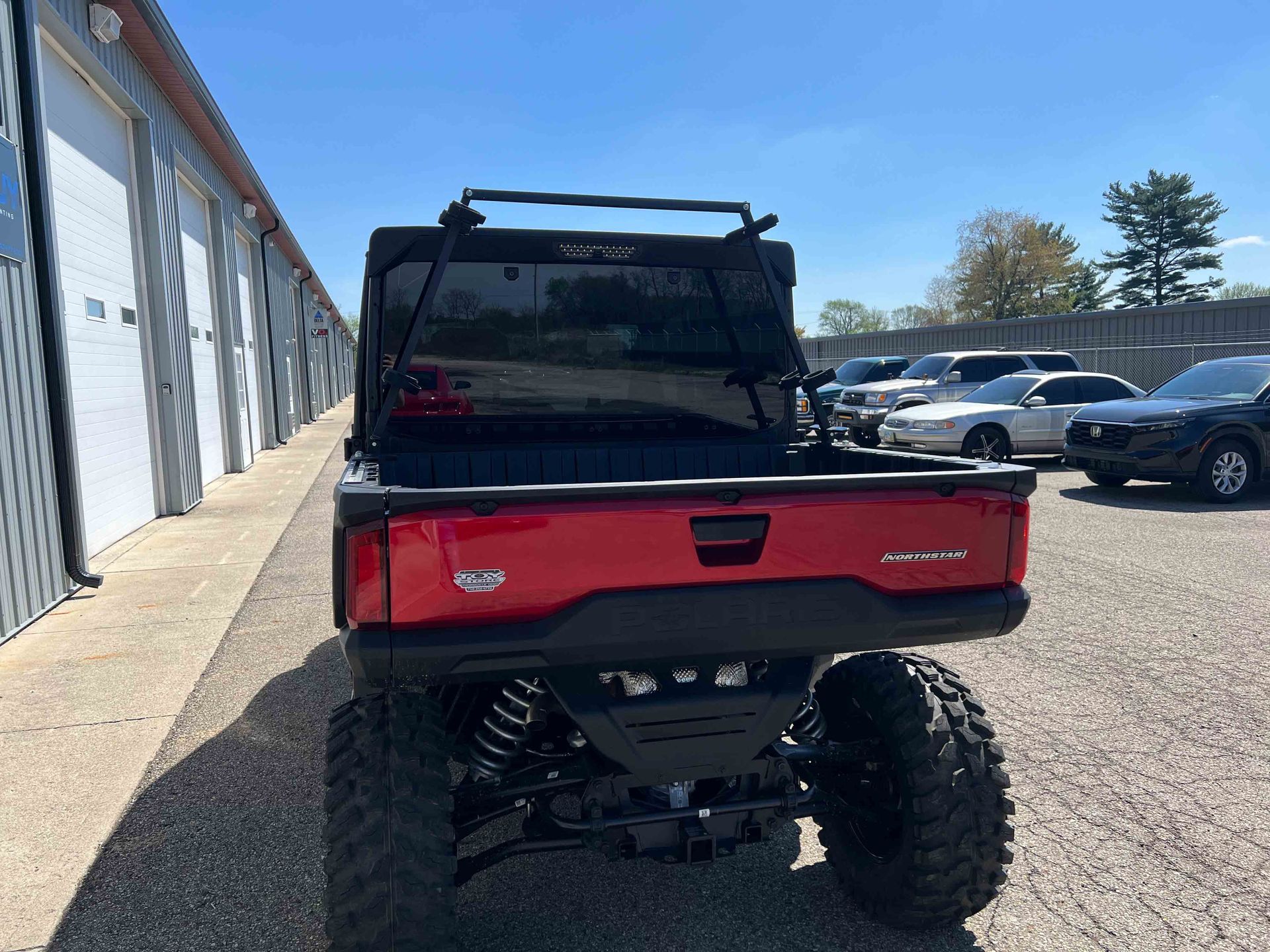 A red atv is parked in a parking lot next to a building.