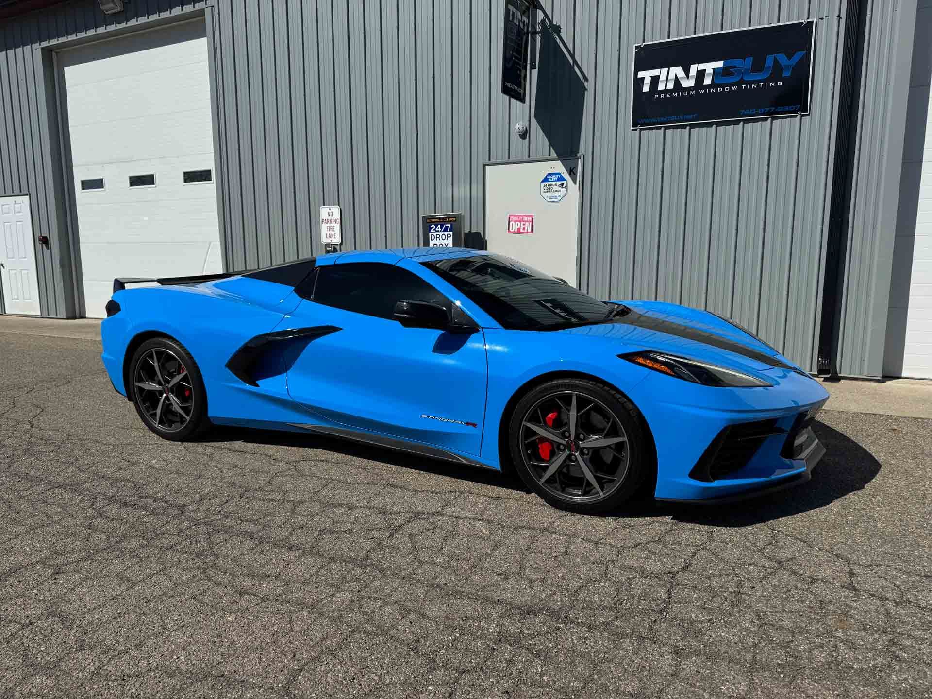 A blue sports car is parked in front of a building.